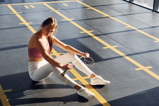In white pants. Beautiful young woman with slim body type is in the gym.