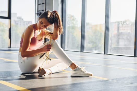 In white pants. Beautiful young woman with slim body type is in the gym.