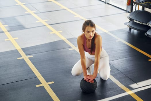 In white pants. Beautiful young woman with slim body type is in the gym.