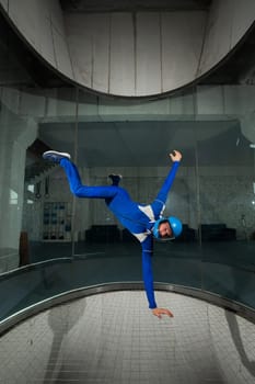 A man in overalls and a protective helmet enjoys flying in a wind tunnel. Free fall simulator.