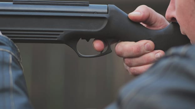 A man firing an air gun. Close-up of her hands