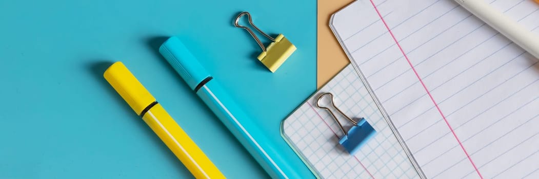 School stationery, color pencils, paints, notepad on blue table. Back to school background. Kids desk top view.