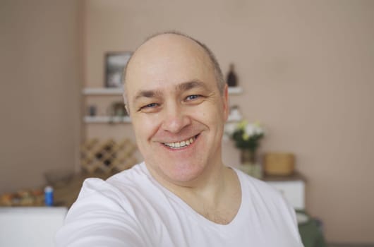 Smiling male blogger taking a selfie or video call from his apartment.