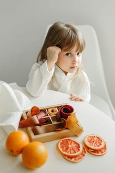 Portrait of a young girl in a dressing gown, who is sitting in the kitchen, next to a box of marmalade, candied fruits.