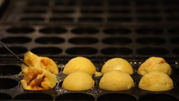 The cooking of Takoyaki. The popular Japanese street food that consists of small, ball-shaped snacks made of batter and filled with small pieces of octopus and other ingredients.