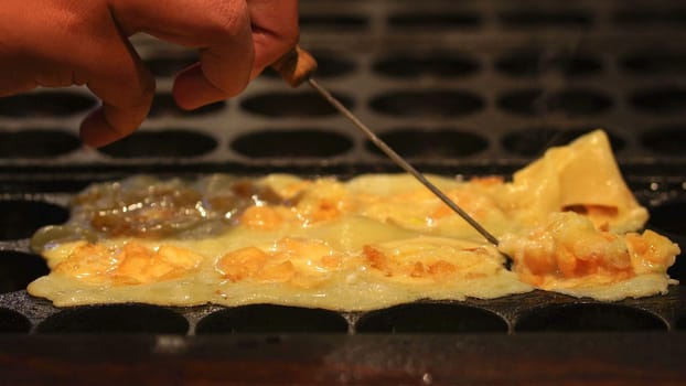 The cooking of Takoyaki. The popular Japanese street food that consists of small, ball-shaped snacks made of batter and filled with small pieces of octopus and other ingredients.