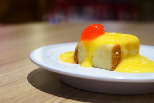 Close up of bread pudding with lemon sauce and cherry topping. Bokeh background and selective focus.