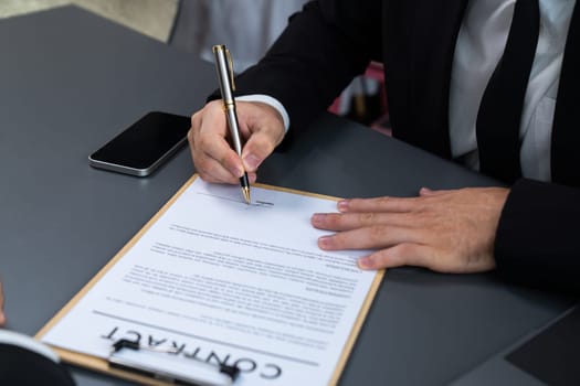 Closeup hand signing contract document with pen, sealing business deal with signature. Businesspeople finalizing business agreement by writing down signature on contract paper. Fervent