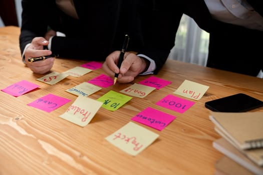 Business team gather on table, brainstorming and writing creative idea on colorful post-it notes. Planning and brainstorm strategy to achieve business targets. fervent