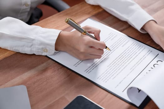 Closeup hand signing contract document with pen, sealing business deal with signature. Businesspeople finalizing business agreement by writing down signature on contract paper. Enthusiastic