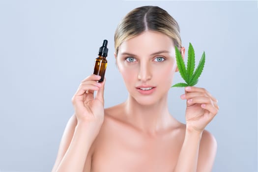 Alluring portrait of beautiful woman in isolated holding green leaf with marijuan extracted bottle for skincare treatment product. Cannabis CBD oil for cosmetology and beauty concept.