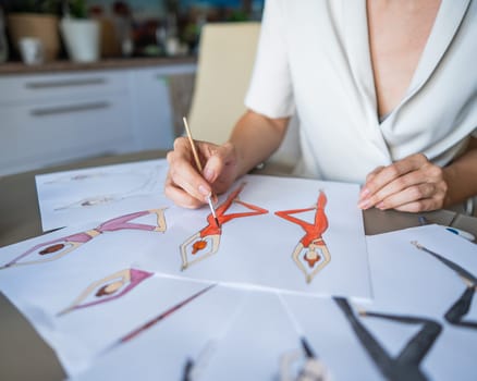 Faceless woman draws watercolor sketches of sportswear. Close-up of the hands of a fashion designer