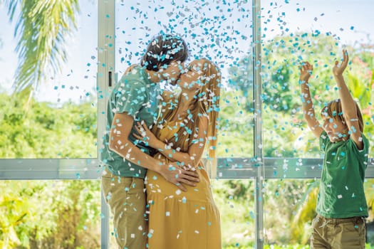 It's a boy. Expectant parents mother, father and their elder son are having a gender reveal party. A married the couple burst the balloon and the blue confetti flew out. Family, pregnancy and prenatal care concept.