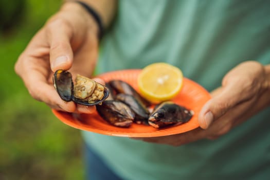 Heap of mussels in shells stuffed with rice. Man is going to eat midye traditional Turkish food. Istanbul, Turkey.