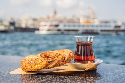 A glass of Turkish tea and bagel Simit against golden horn bay in Istanbul, Turkey. Turkiye.