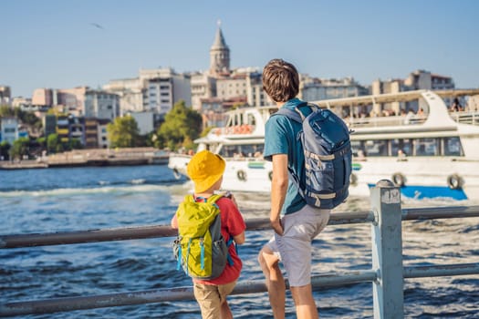 Father and son tourists enjoy Istanbul city skyline in Turkey, Beyoglu district old houses with Galata tower on top, view from the Golden Horn.