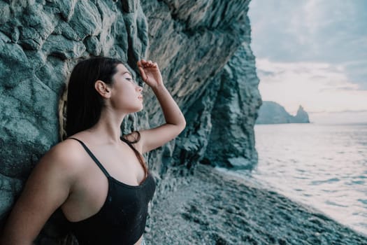 Portrait of cheerful female climber ascending a rock. The athlete girl trains in nature. Woman overcomes difficult climbing route.