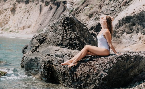 Woman travel sea. Young Happy woman in a long red dress posing on a beach near the sea on background of volcanic rocks, like in Iceland, sharing travel adventure journey