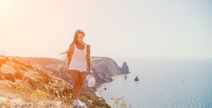 Woman travel sea. Young Happy woman in a long red dress posing on a beach near the sea on background of volcanic rocks, like in Iceland, sharing travel adventure journey