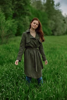 a beautiful woman stands in a field in a long raincoat enjoying nature. High quality photo