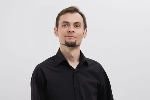Caucasian man 30s with a beard in a black shirt bust portrait on white background.