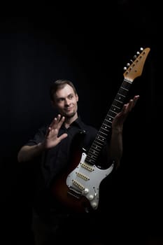 The guitarist masterfully controls the electric guitar, studio portrait on a black background.