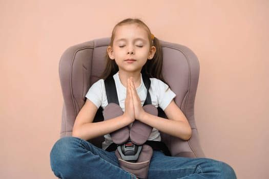 Funny happy caucasian girl of primary school age feels calm and safe in a car seat.