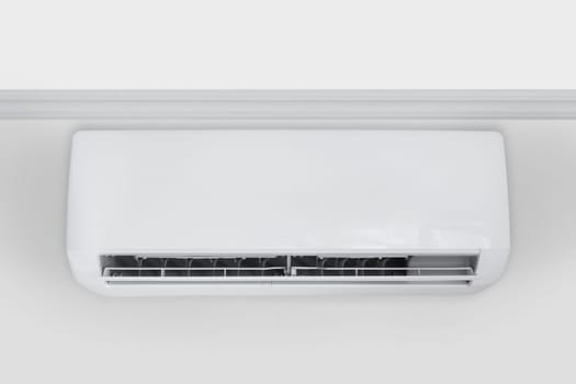 Front view on White air conditioner hanging from the ceiling on the bright wall, copy space.