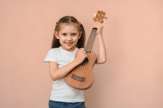 Caucasian smiling happy elementary school age girl learning music playing guitar.