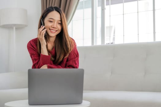 Satisfied asian woman relaxing on comfortable couch, using laptop at home, happy girl chatting with friends in social network, spending lazy weekend, watching movie, shopping online, writing email..