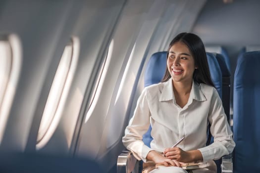 Young, beautiful girl the passenger seat in a charter plane or business jet near the porthole and smiles..