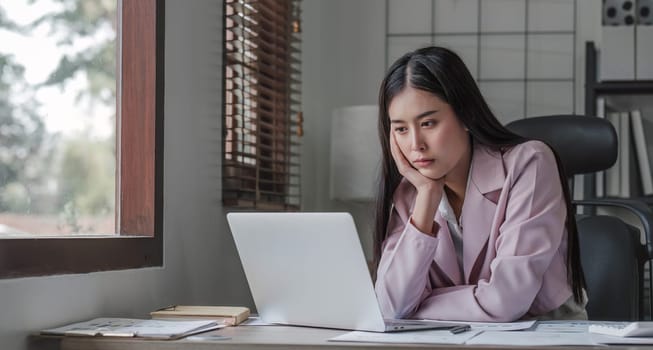 asian woman thinking hard concerned about online problem solution looking at laptop screen, worried serious asian businesswoman focused on solving difficult work computer task...