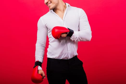 Handsome young businessman with a boxing gloves. Studio red background