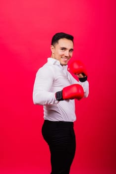 Handsome young businessman with a boxing gloves. Studio red background