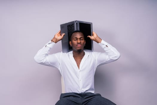 Optimistic african-american male student in a casual shirt using laptop pc isolated