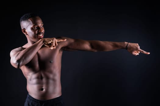 One young african muscular build man standing topless silhouette isolated on a black background