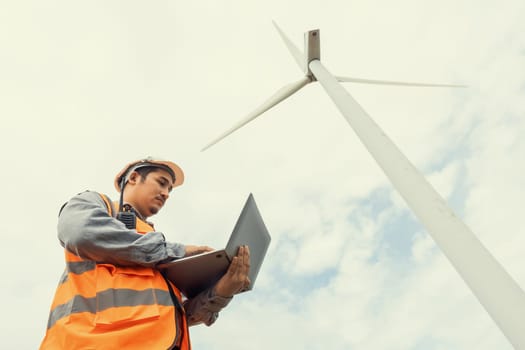 Engineer working on a wind farm atop a hill or mountain in the rural. Progressive ideal for the future production of renewable, sustainable energy. Energy generation from wind turbine.