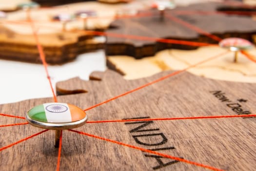 India flag on the pushpin and red thread on the wooden map, close up. Mark of visiting places and planning of vacation and travel routes.