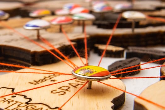 Spain flag pins and red thread for traveling and planning trips. Planning of logistics routes or spheres of influence in geopolitics
