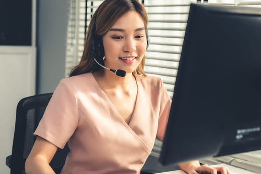 Competent female operator working on computer and while talking with clients. Concept relevant to both call centers and customer service offices.