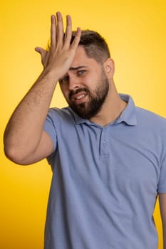 Face palm. Shame on you. Upset confused young man making face palm gesture, feeling bored uncertain, disappointed in result, bad news. Handsome guy isolated alone on yellow studio background indoors