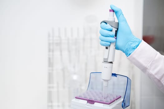 Close up scientist hand takes plastic tip for automatic pipette from the box for sample collection. Medical research laboratory.