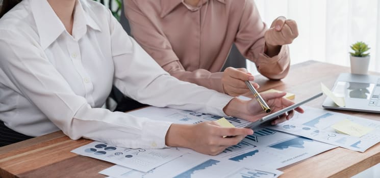 Analyst team colleague discuss financial data on digital dashboard, analyzing charts graph display on laptop and tablet screen. Modern office use business intelligence to plan marketing. Enthusiastic