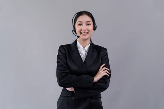 Attractive asian female call center operator with happy smile face advertises job opportunity on empty space, wearing a formal suit and headset on customizable isolated background. Enthusiastic