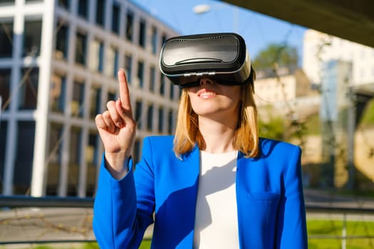 Young woman touching the air using a virtual interface by pressing buttons finger in virtual reality glasses near business center.