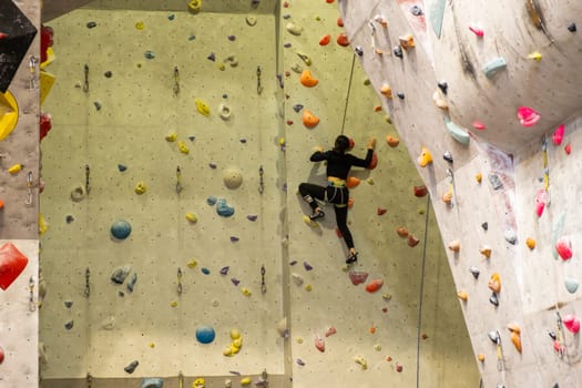The climber trains on the artificial rock wall with insurance in bouldering gym, April 2022, Prague, Czech Republic.