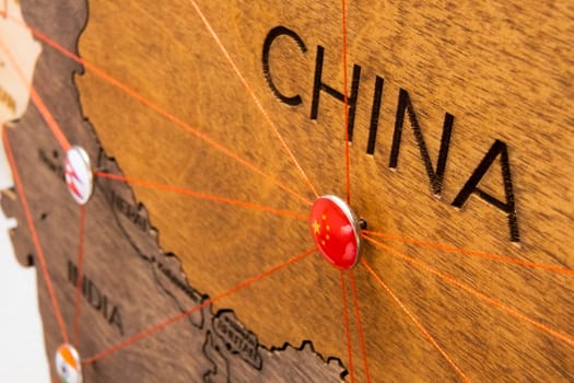 China flag on the pushpin and red thread on the wooden map, close up. Mark of visiting places and planning of vacation and travel routes.