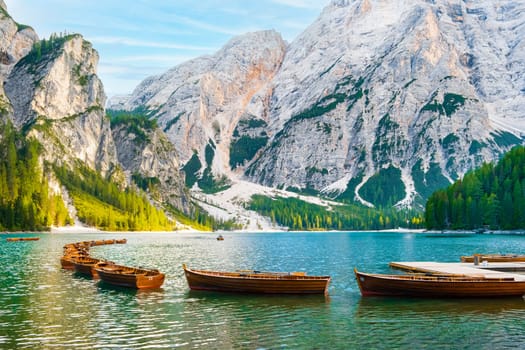 Wooden boats on the popular tourist lake Braies with amazing view of Dolomites Alps