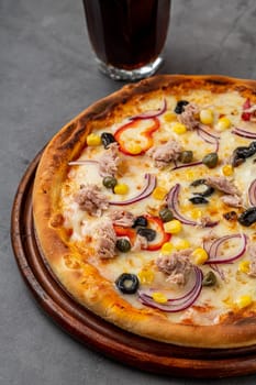 Pizza with tuna, onions and olives on cutting board on stone table