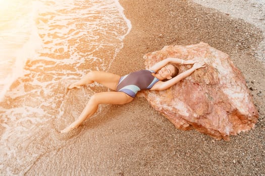 Woman travel sea. Young Happy woman in a long red dress posing on a beach near the sea on background of volcanic rocks, like in Iceland, sharing travel adventure journey